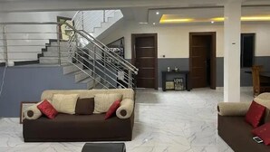 A spacious living area with a modern staircase, a sofa set, and a coffee table. - Prego Apartment  (Abuja)