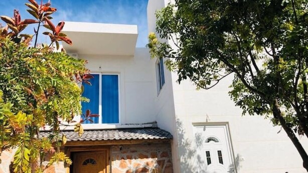A white building with a stone entrance, a blue window, and a door. - Olympia Triple Room – Cozy & Central Stay for 3 Guests (Fishta)