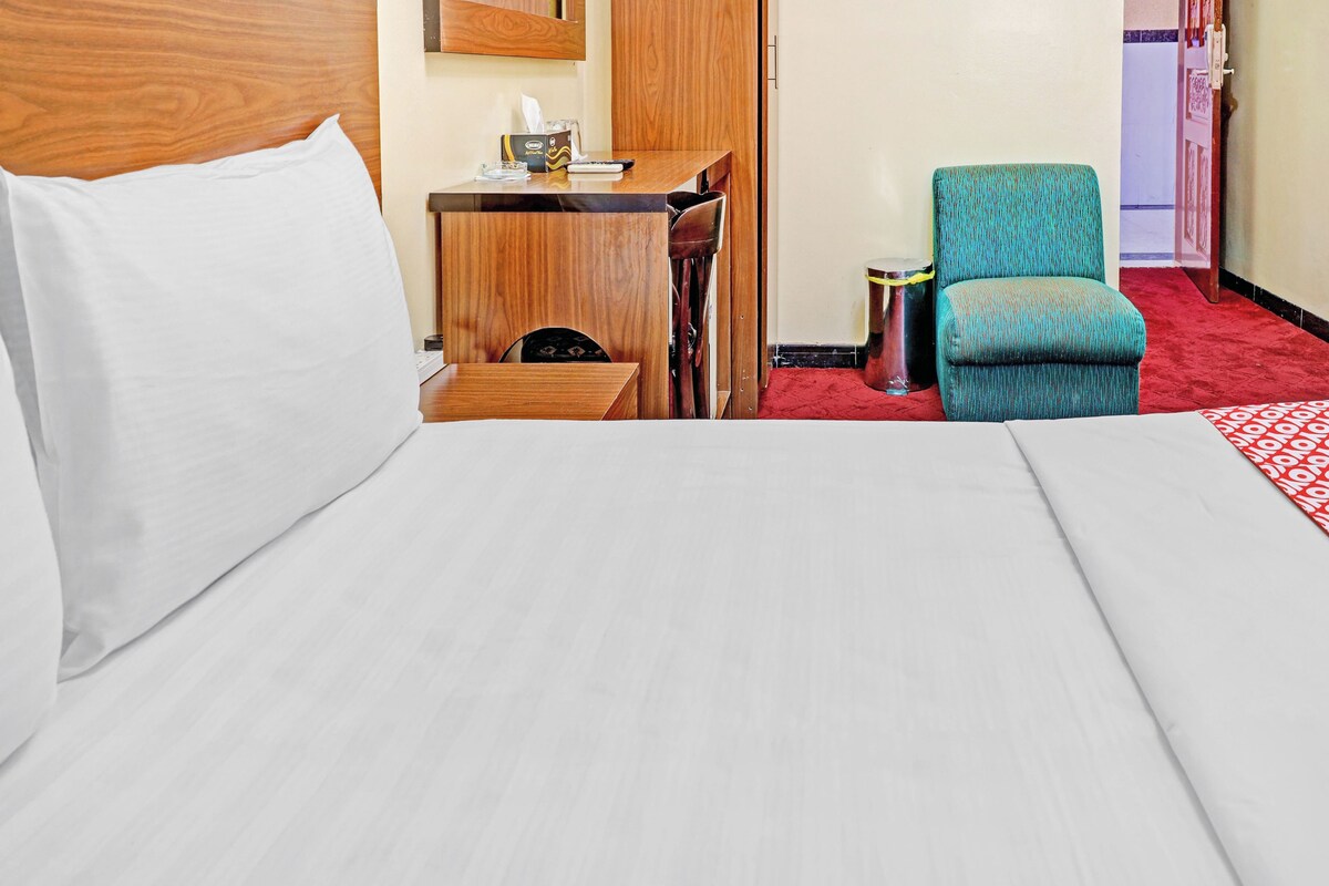 Una habitación de hotel con una cama, un escritorio, una silla y un bote de basura.
