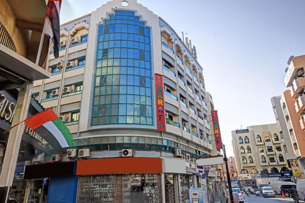 A multi-story hotel with a curved facade, multiple balconies, and a prominent sign reading "CARAF HOTEL".