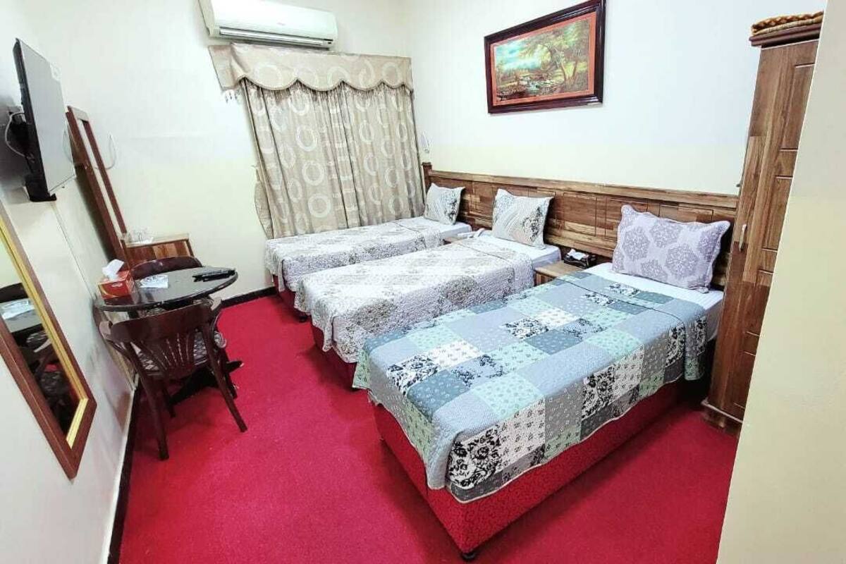 A hotel room with two beds, a desk, a chair, and a TV.