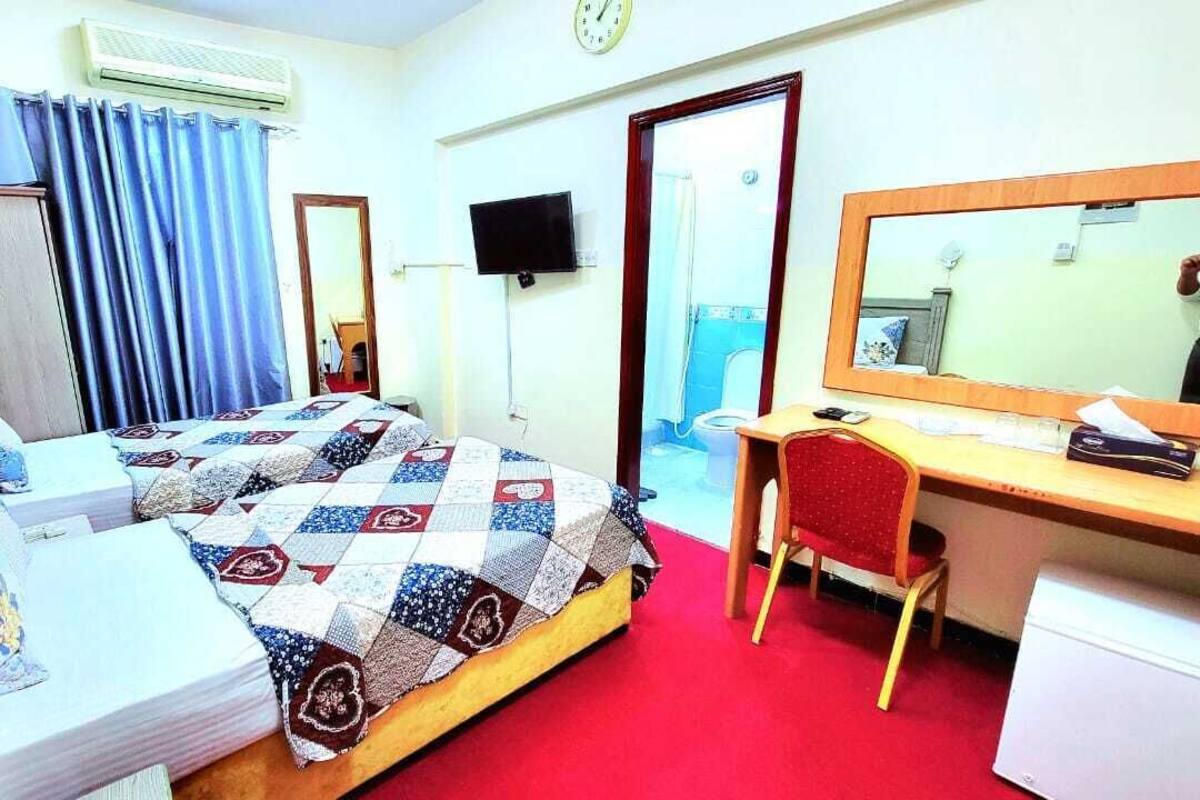 A hotel room with a bed, a desk, a chair, a television, and a mirror.