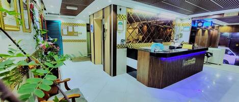 A reception area with a wooden reception desk, a blue-lit counter, and a tiled floor.