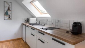 Et moderne køkken med ovenlys, hvide skabe og en træbordplade.