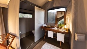 A compact bathroom with a wooden vanity, a sink, and a mirror. - Basecamp Wilderness (Maasai Mara)