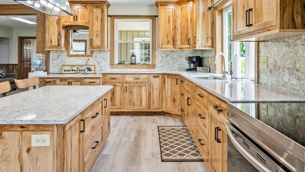 Eine Küche mit Holzausstattung, Granit Arbeitsplatten und einer großen Kochinsel.