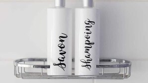 Two white shampoo bottles with black cursive text on a clear metal shelf against a white tiled wall. - 🏖 5 min from Bénodet and the ocean - comfortable rooms with SPA included 🌿 (Pleuven)