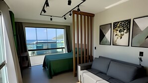 A modern room with a sofa, a dining table, and a view of the sea. - LOFT BRISA 106 (Arraial do Cabo)
