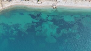 Eine Vogelperspektive zeigt einen Strand mit klarem türkisblauem Wasser und einem sandigen Ufer.