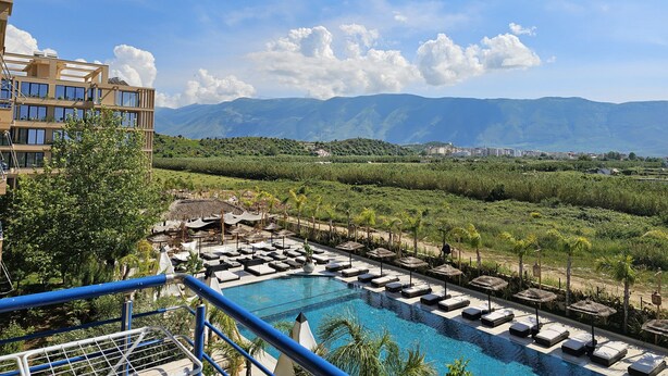 Ein Resort mit Pool, Liegestühlen und Bergblick.