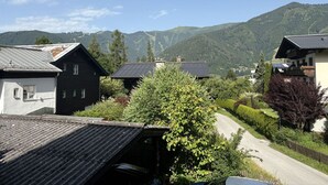 Een landelijk dorp met traditionele huizen, een kronkelende weg en bergen op de achtergrond.