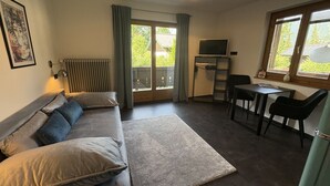 Een moderne woonkamer met een bank, een salontafel, een televisie en een eethoek met stoelen.