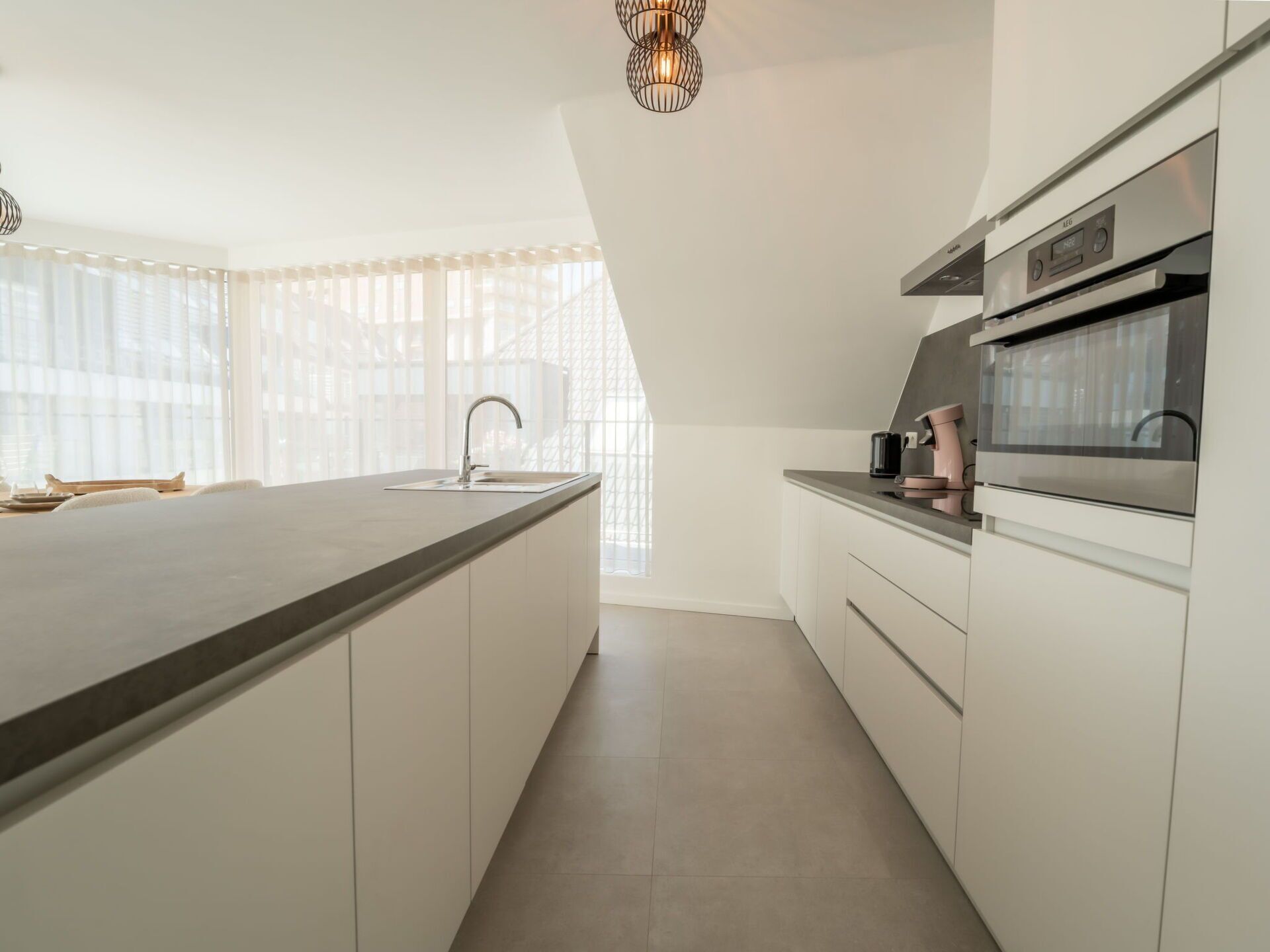 A modern kitchen with a large island, stainless steel appliances, and a pendant light.