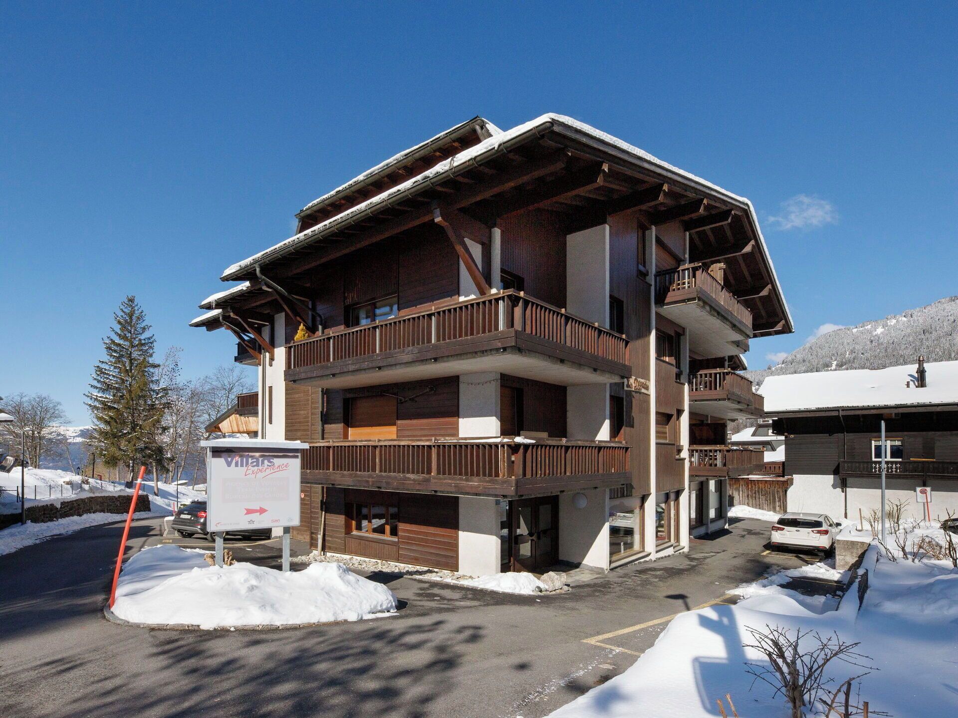 A multi-story building with balconies, a signboard, and snow-covered surroundings.