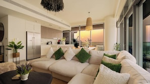 A modern living room with a sofa, a coffee table, and a kitchen in the background. - KeyRock - Sea View Beachfront Penthouse (Dubai)