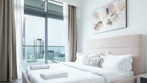 A modern hotel room with a large bed, a view of the city, and a framed artwork on the wall. - KeyRock - Sea View Beachfront Penthouse (Dubai)