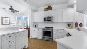 Una cocina moderna con armarios blancos, microondas, horno y cafetera.