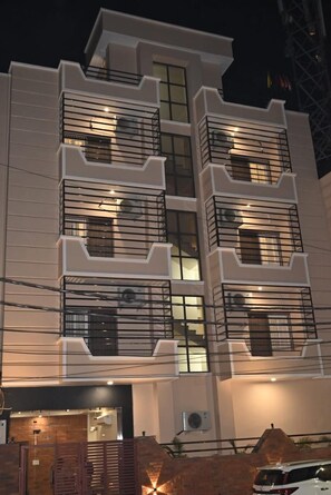 A multi-story building with balconies and a gated entrance.