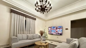 Ein modernes Wohnzimmer mit einem grauen Sofa, einem runden Couchtisch, einem Fernseher und einem Weihnachtsbaum.