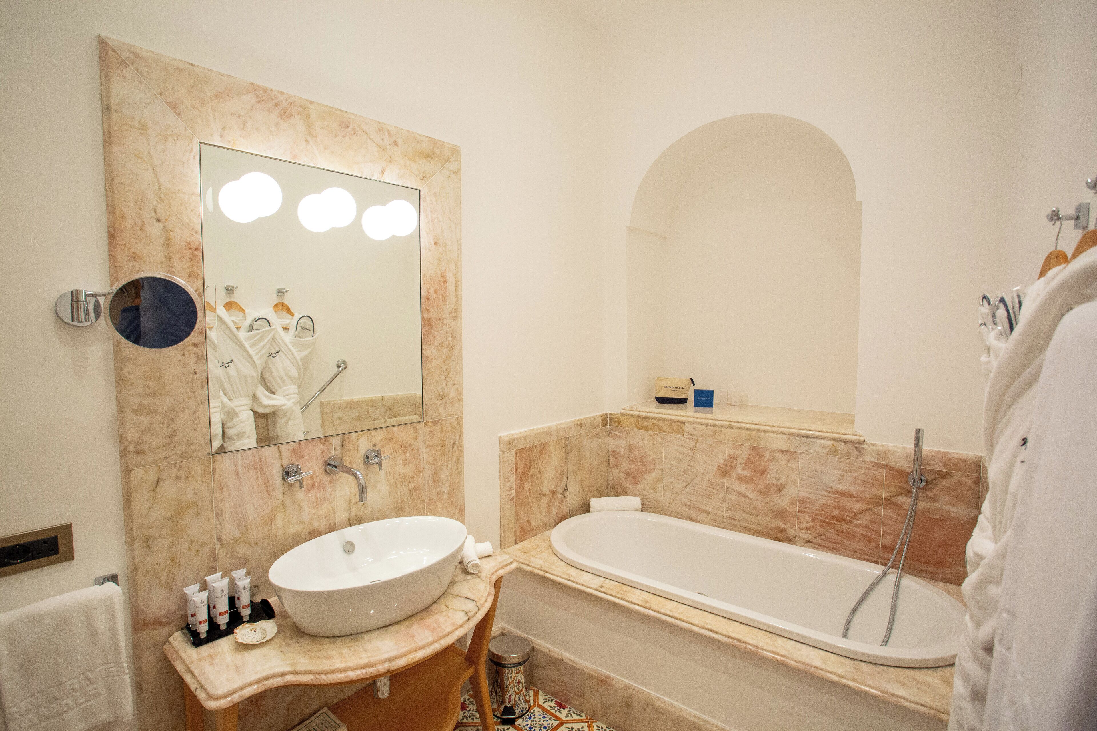 Une salle de bain moderne avec un grand miroir, un lavabo et une baignoire.