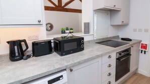 Une cuisine moderne avec des meubles blancs, une machine à café Bosch, un four à micro-ondes et un lave-vaisselle.