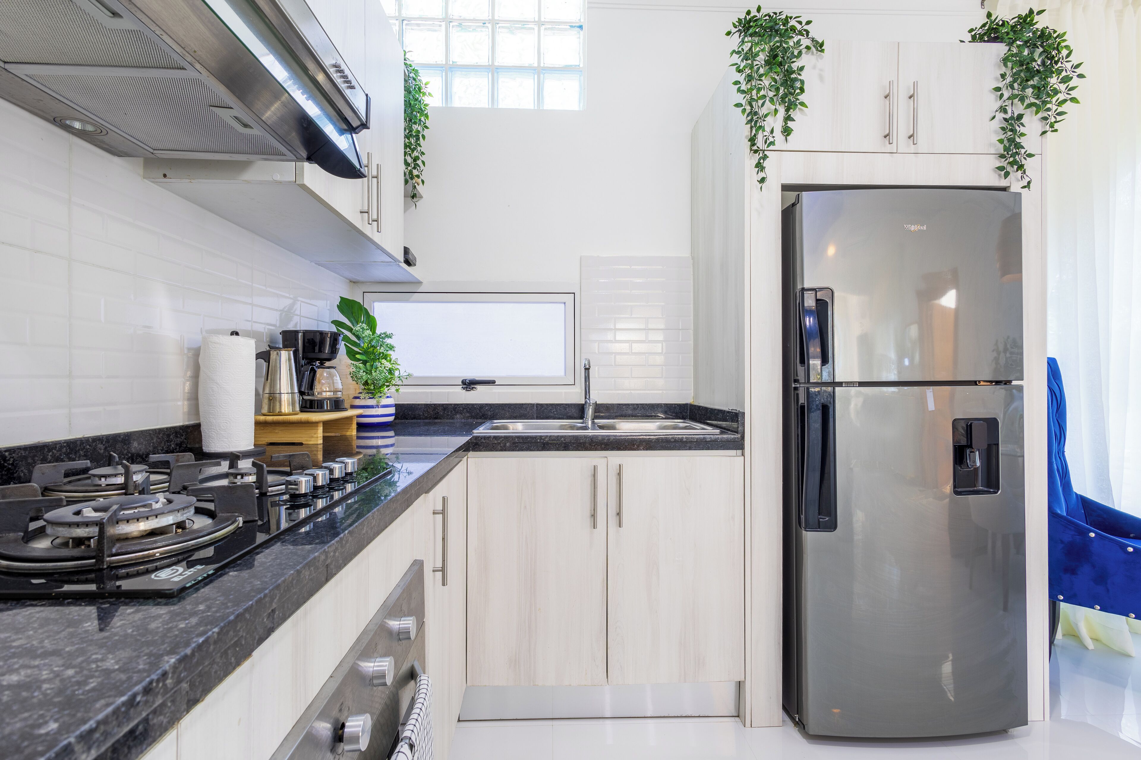 A modern kitchen with a stainless steel refrigerator, a gas stove, and light wooden cabinets.
