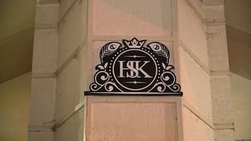 Un letrero negro con las letras 'ISK' en una tipografía decorativa, sujeto a una pared beige con textura.