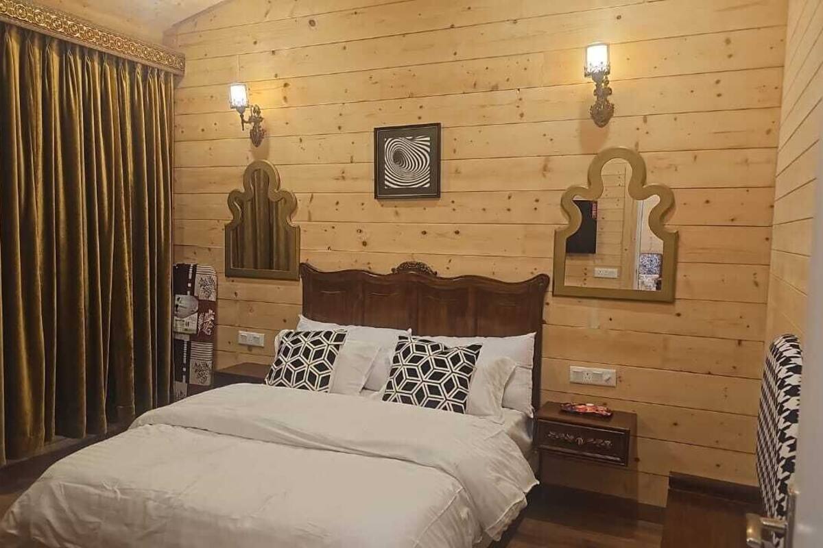 A wooden-paneled bedroom with a bed, two wall-mounted lamps, and a decorative mirror.