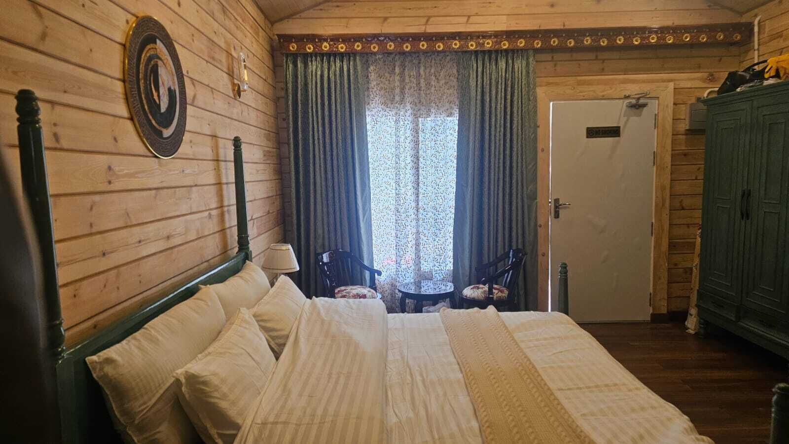 A wooden-paneled room with a bed, two chairs, a small table, and a door labeled 'MOTEL.'
