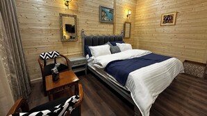 Une pièce aux murs lambrés, comprenant un lit, des tables de chevet, une chaise et des lampes fixées au mur.