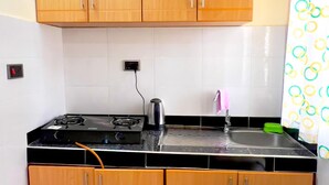 A kitchen with wooden cabinets, a stove, and a sink. - Zotel leisure courts kisigula  (Mbarara)