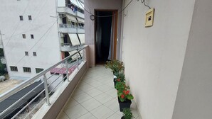 Parvekkeessa on laatoitettu lattia, metallikaide ja ruukuissa olevia kasveja.