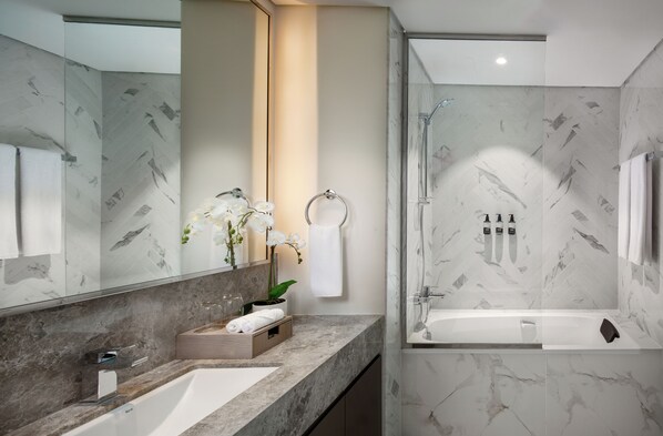A modern bathroom with a marble sink, a glass shower enclosure, and a large mirror.