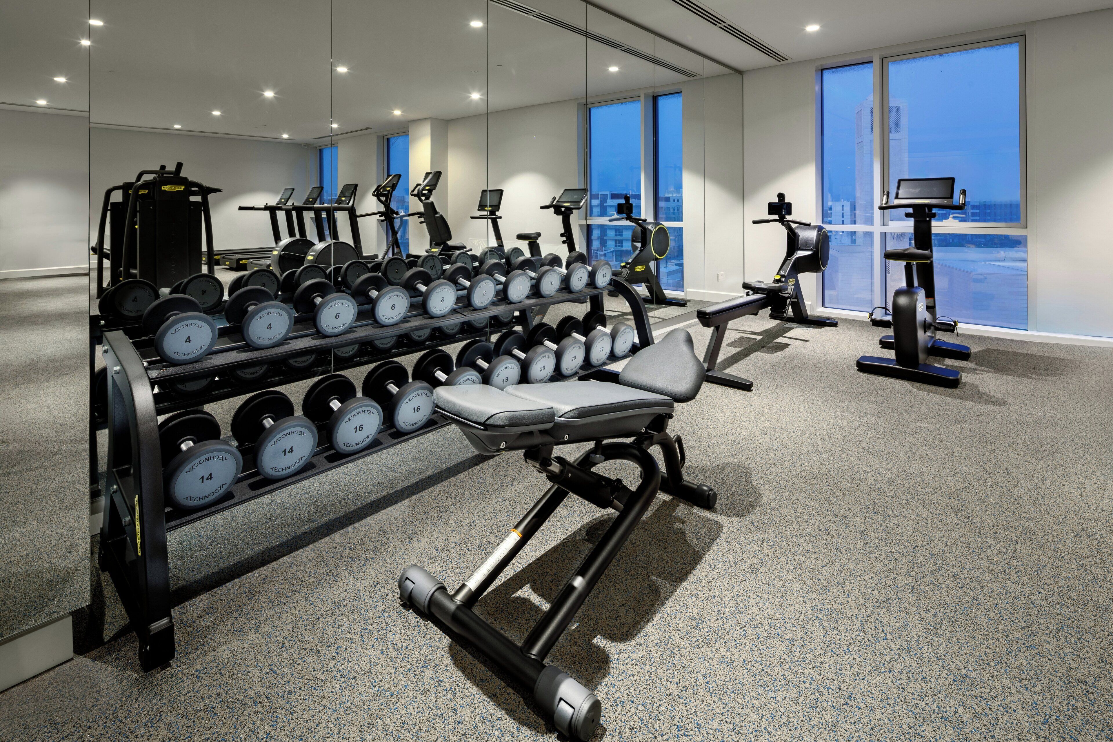 A modern gym with various exercise equipment, including dumbbells, treadmills, and weight machines.