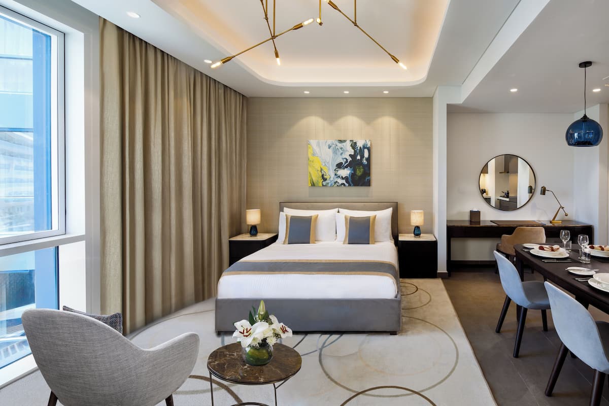 Una habitación de hotel moderna con una cama grande, un escritorio y una zona de comedor.