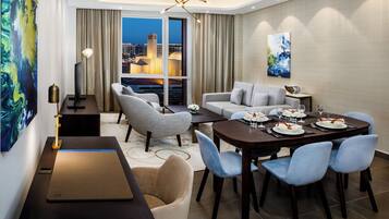 A modern hotel room with a dining area, a sofa set, and a city view.