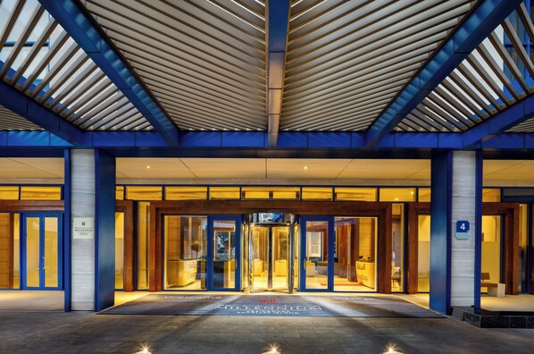 A hotel entrance with a modern design, featuring a glass door entrance, a central revolving door, and a blue and yellow color scheme.
