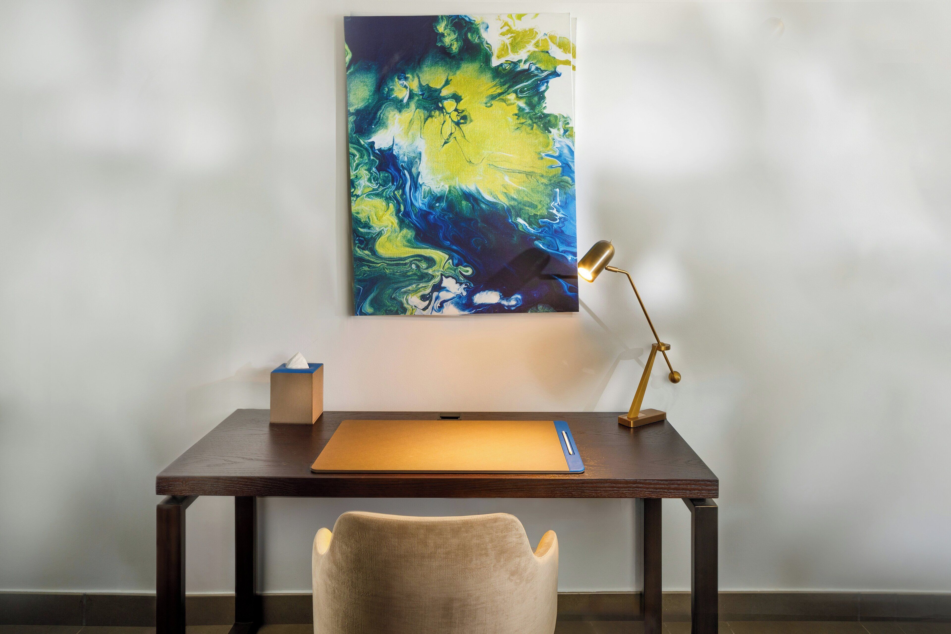 A desk with a laptop, a lamp, and a tissue box.