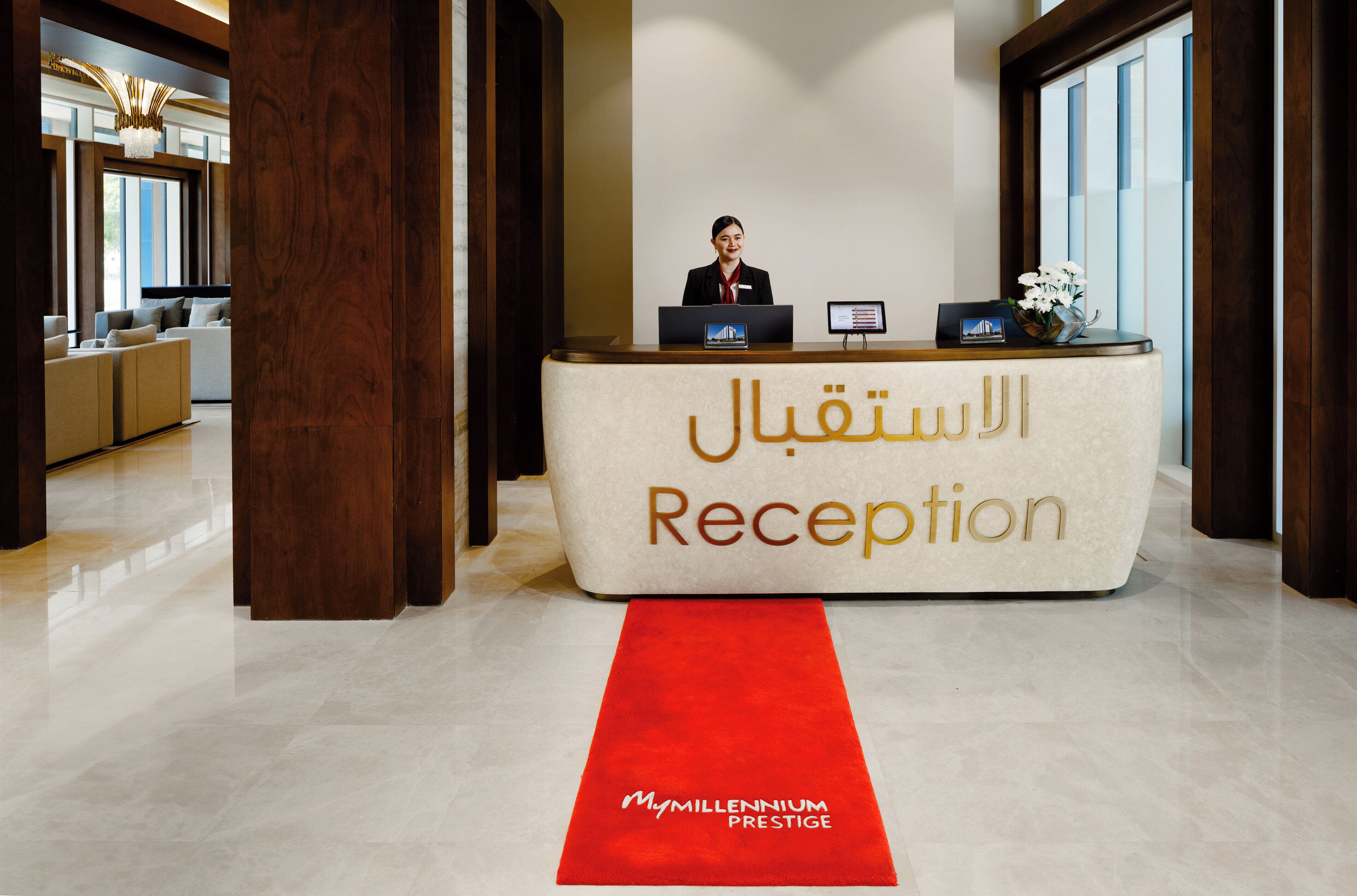 A reception desk with a receptionist, a red carpet, and a sign that reads "MyMillennium Prestige".