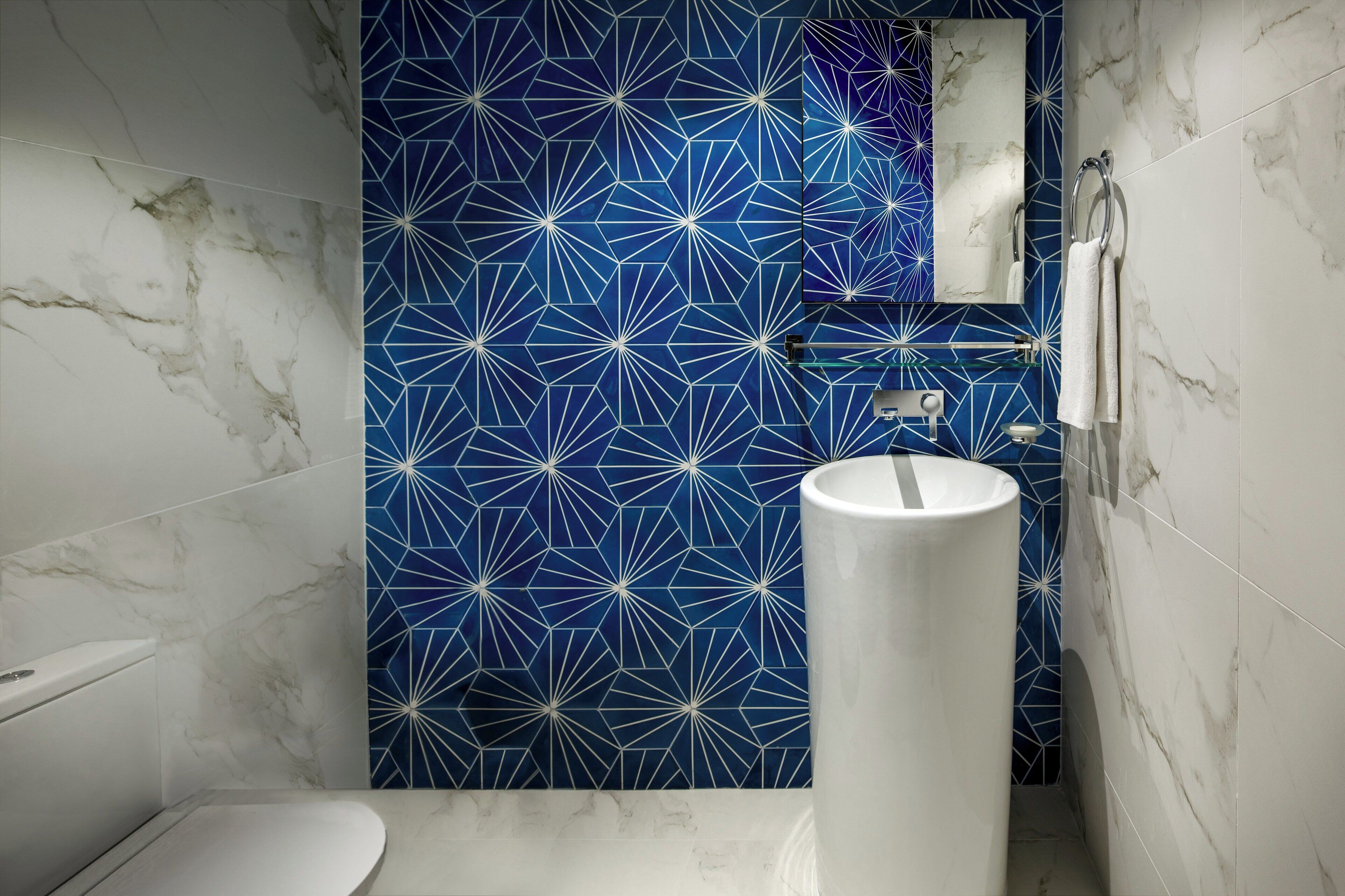 A bathroom with a white toilet, a white sink, and a blue geometric-patterned wall.