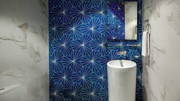 A bathroom with a white toilet, a white sink, and a blue geometric-patterned wall.
