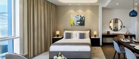A modern hotel room with a large bed, a desk, and a dining area.