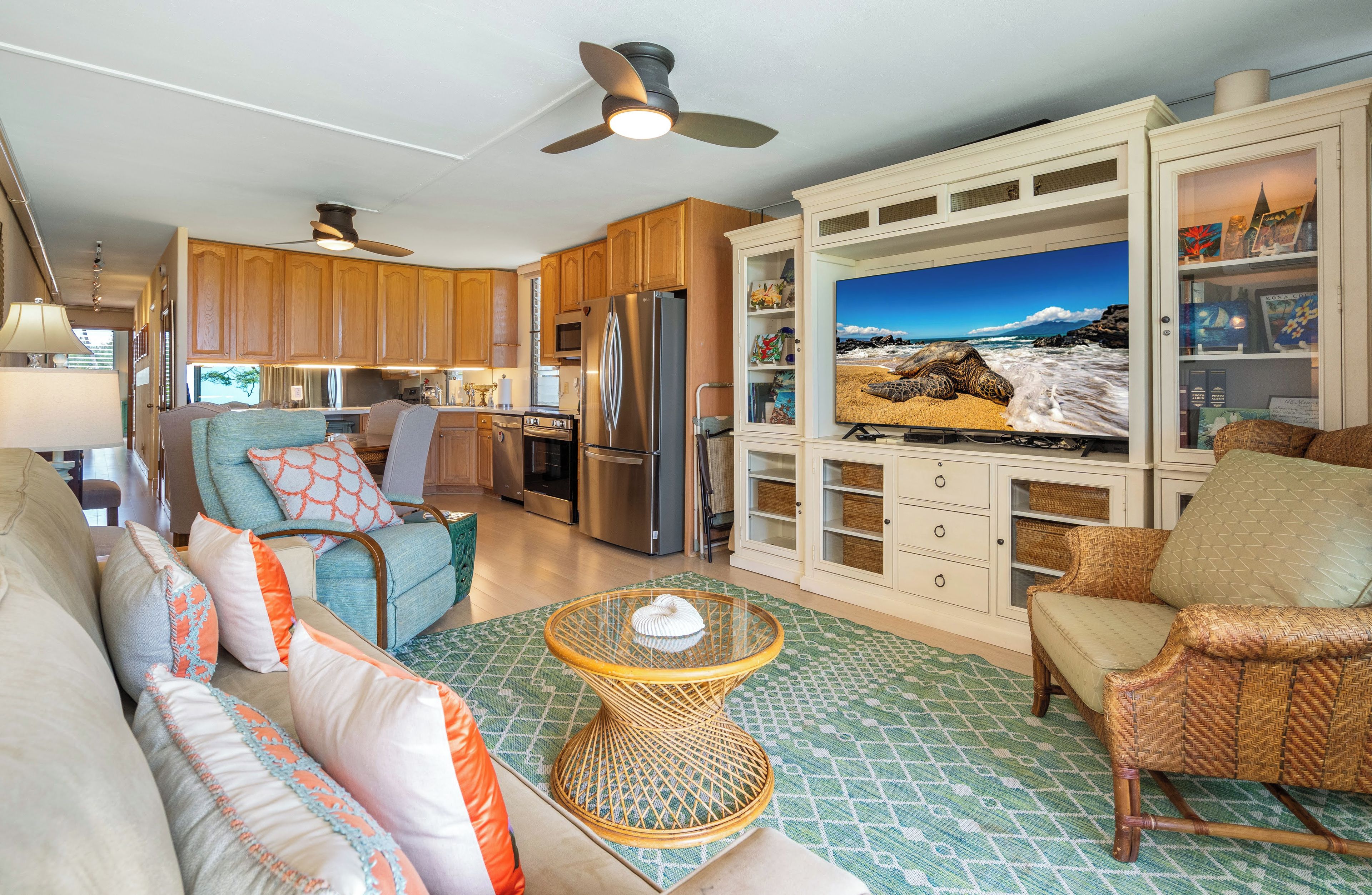 A compact living space with a kitchenette, a sofa set, a television, and a ceiling fan.