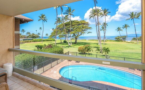 Une piscine offrant une vue dégagée sur l’océan, avec des palmiers en arrière-plan.