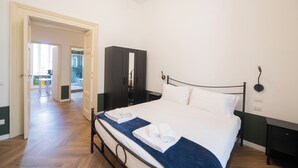 Une chambre d’hôtel avec un grand lit, une armoire, un bureau et une salle de bain visible à travers une porte ouverte.