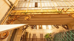 Une vue architecturale d’un bâtiment doté d’un balcon, de volets en bois et d’un portail en métal.
