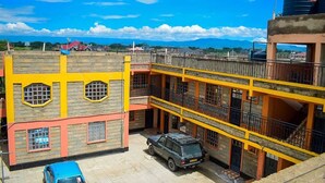 A multi-story building with a yellow and red facade, featuring a car parked in the courtyard.