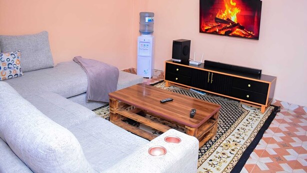 A living room with a sofa, a coffee table, a TV, and a water dispenser.