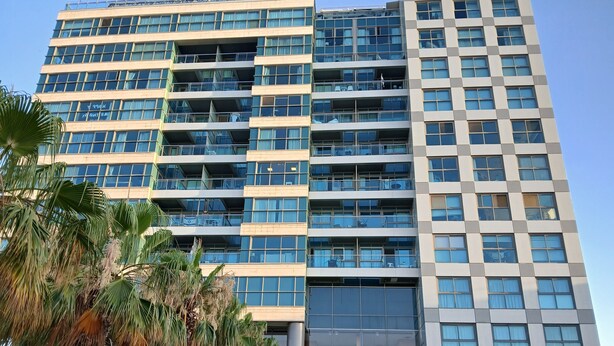 Un hotel de varios pisos con un diseño arquitectónico moderno, que cuenta con balcones en cada planta y ventanas amplias.