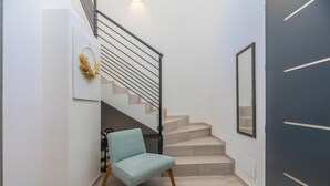 Una escalera con una silla azul claro y un espejo fijado a la pared.